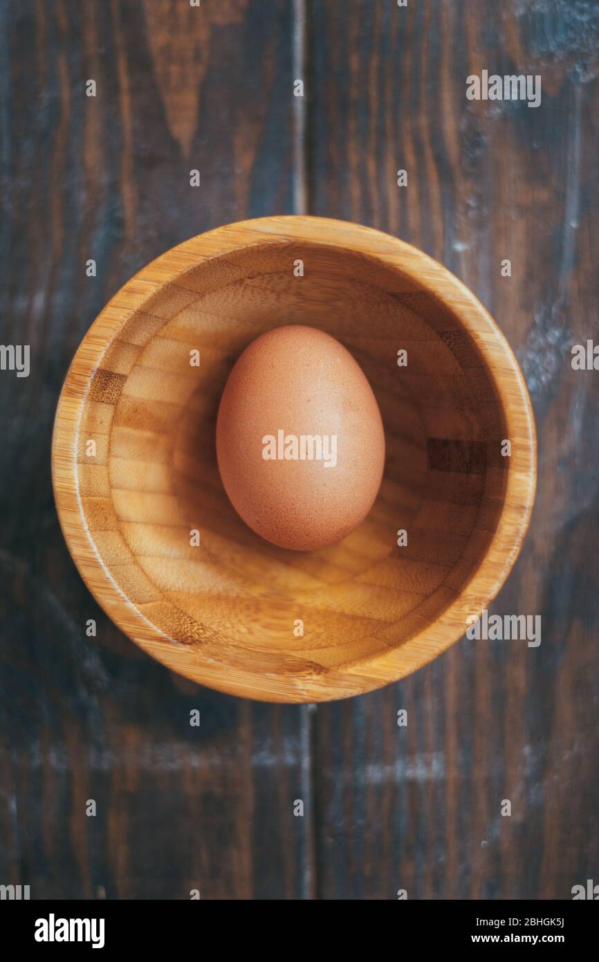 Uovo biologico in una ciotola di legno su un tavolo di legno Foto Stock