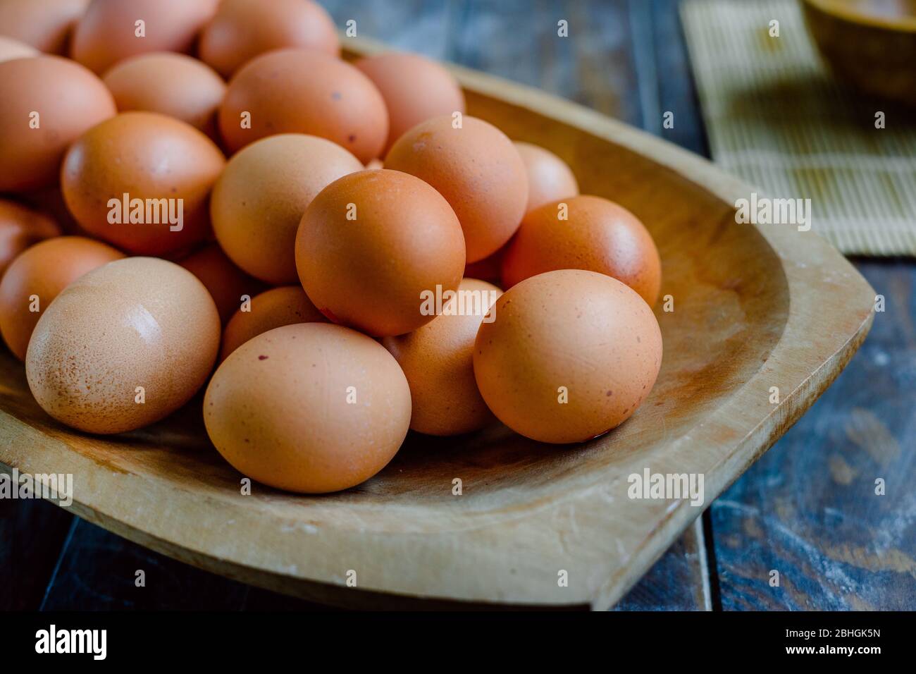 Uova biologiche in una grande ciotola di legno su un tavolo di legno Foto Stock