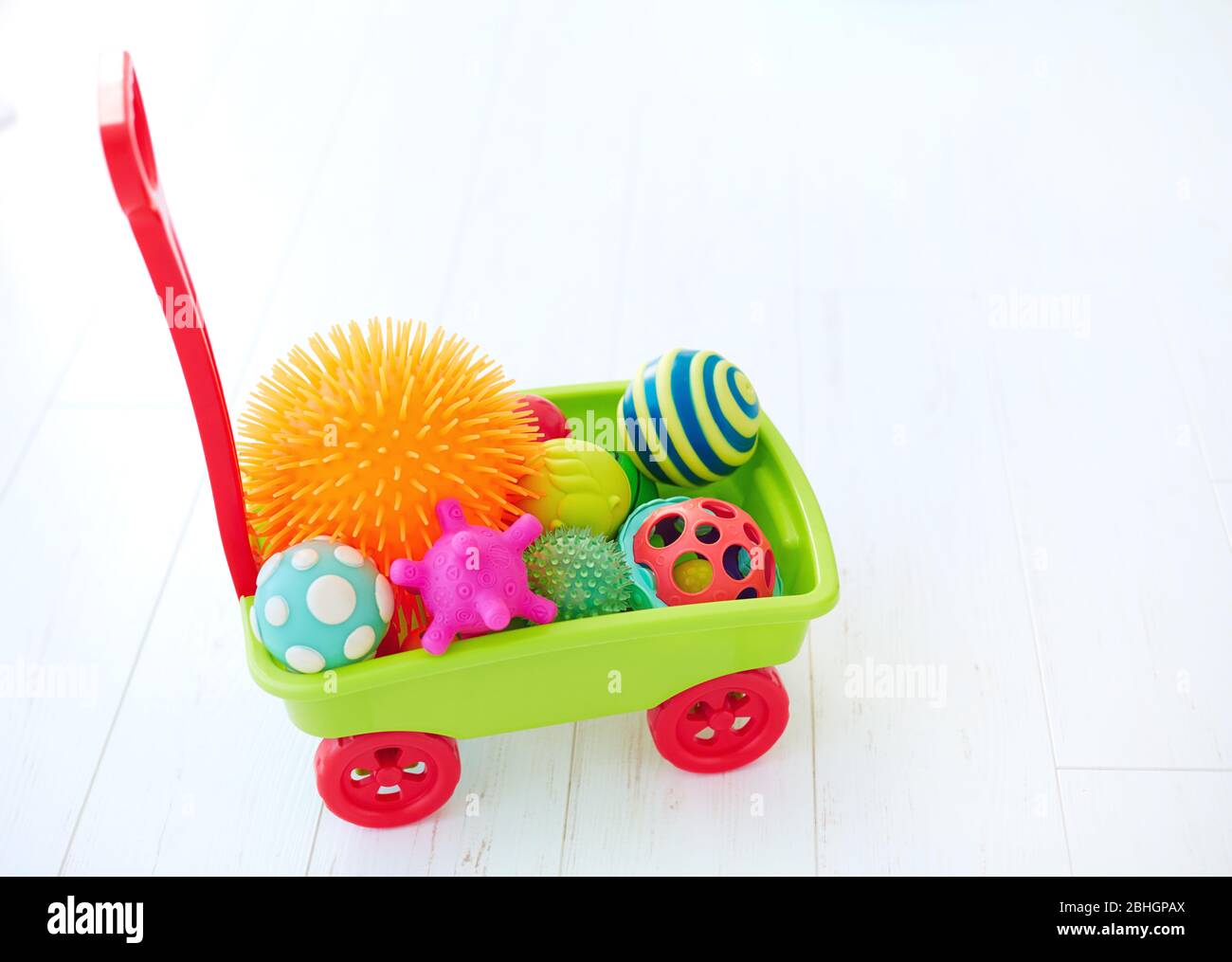 carrello giocattolo colorato pieno di palline tattili di diverso colore e forma per lo sviluppo dei bambini Foto Stock