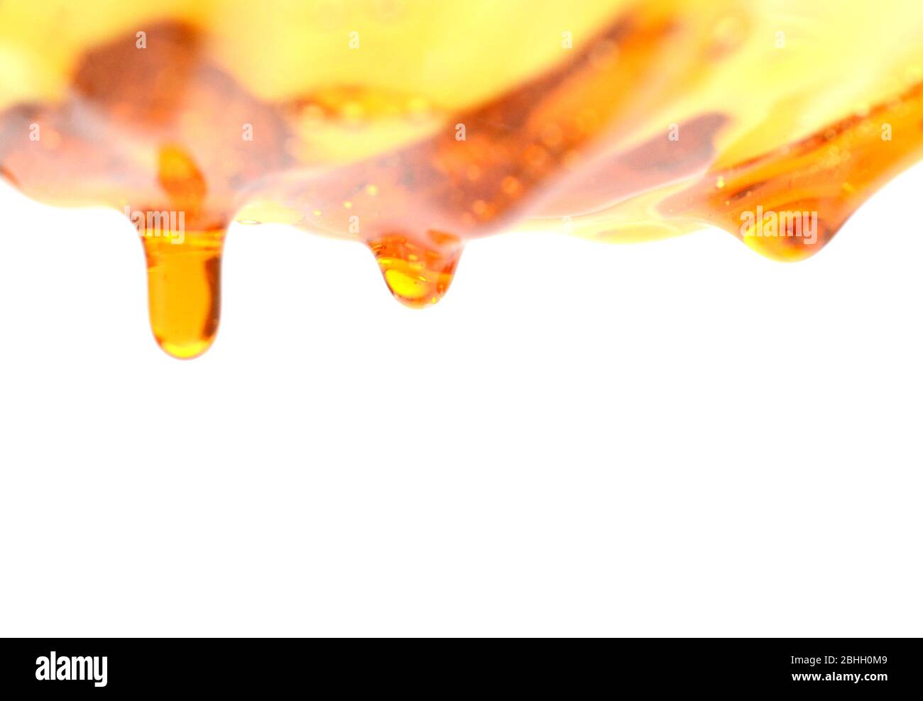 Il miele che scorre su sfondo bianco Foto Stock