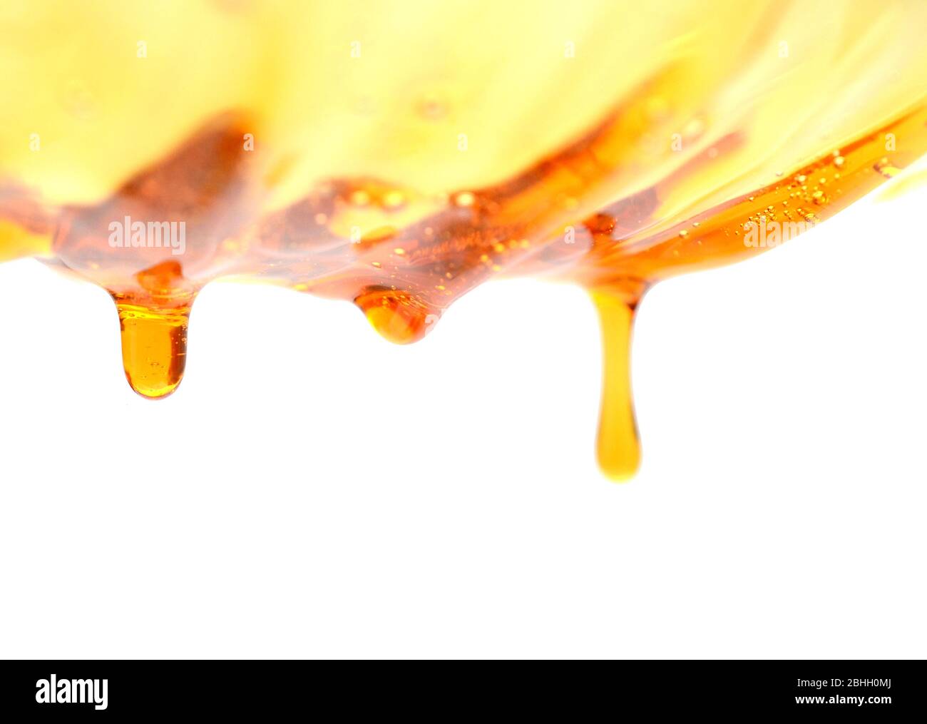 Il miele che scorre su sfondo bianco Foto Stock