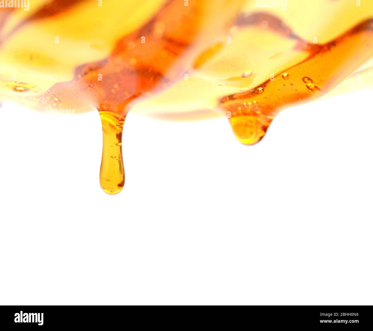 Il miele che scorre su sfondo bianco Foto Stock