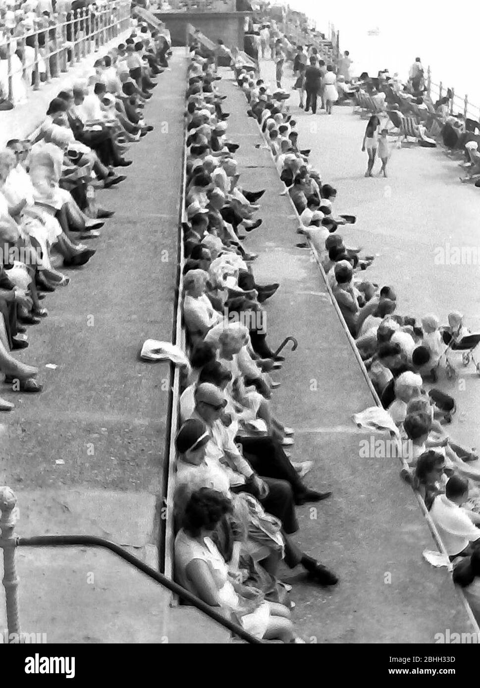 Le persone in vacanza si siedono lungo la passeggiata che guarda al mare a Blackpool, Lancashire, Inghilterra, Regno Unito, all'inizio degli anni '70. Foto Stock