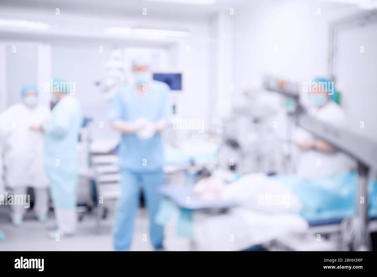 Astratto medico offuscato sfondo della sala operatoria, paziente si trova sul tavolo, medici che lavorano Foto Stock