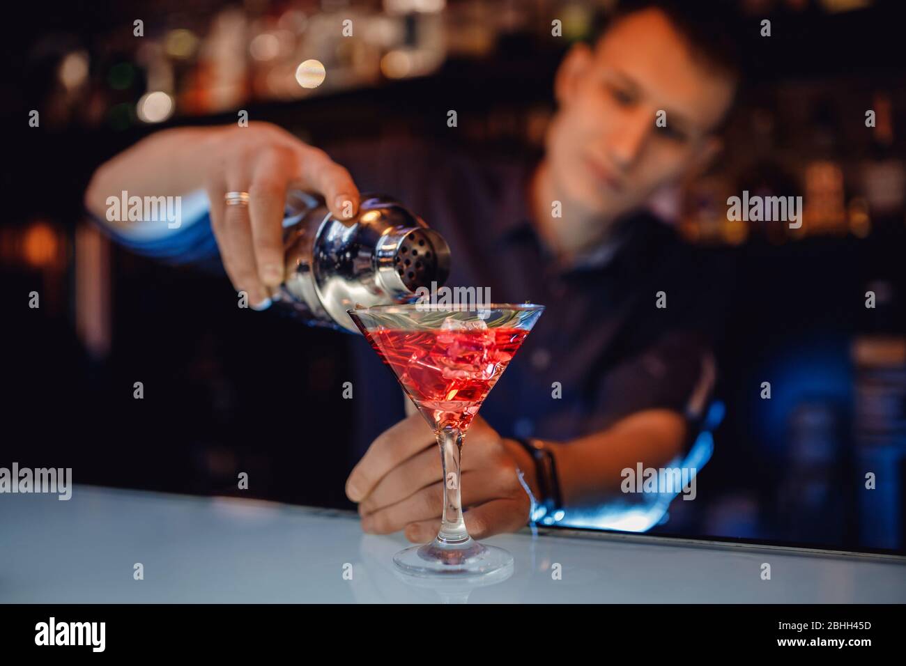 Il barman sta preparando un cocktail in shaker di alcool rosso e vetro ghiacciato, bar counter Foto Stock