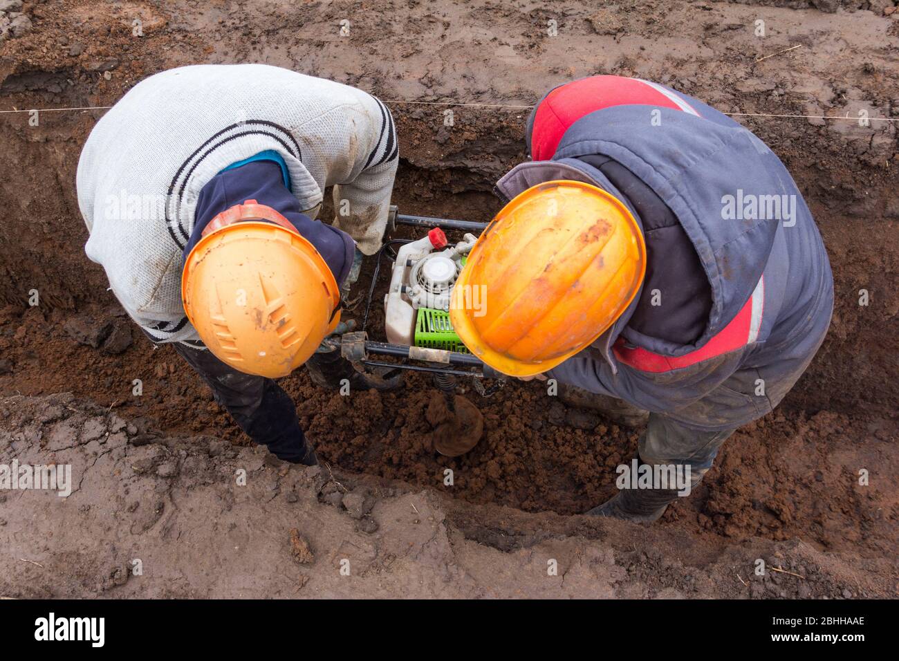 Due lavoratori foro di scavo per montante di fence. Installazione di recinzioni da costruzione Foto Stock