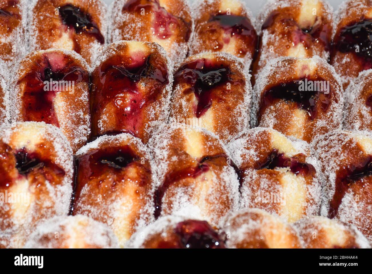 Molte ciambelle poste in un vassoio, per la vendita al mercato alimentare. Primo piano ciambelle in vendita nel panificio al supermercato. Deliziosa colazione con dessert per il caffè Foto Stock