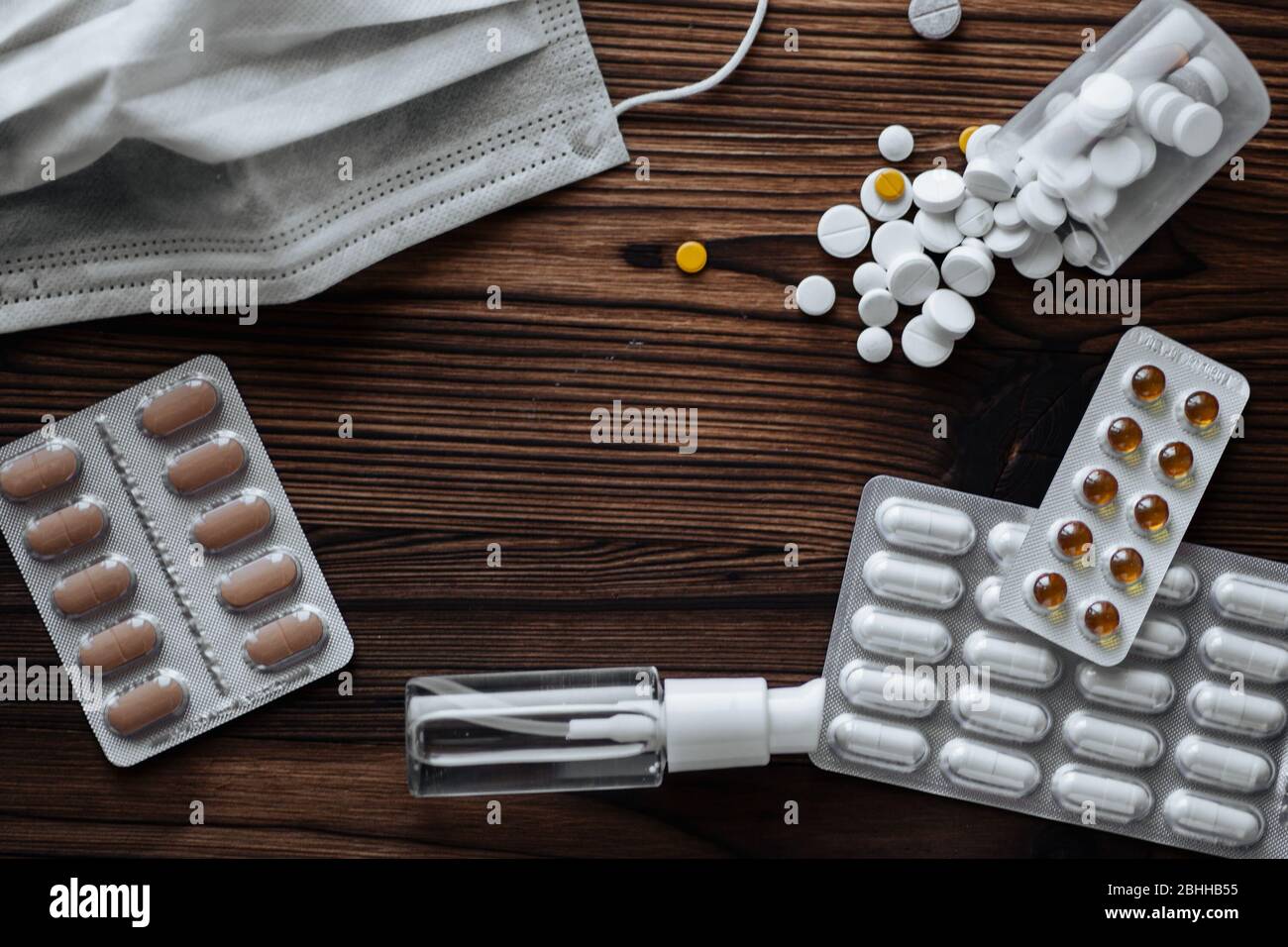 Maschera medica protettiva, pillole e gel antisettico per le mani su fondo in legno. Concetto di medicina, quarantena. Foto Stock