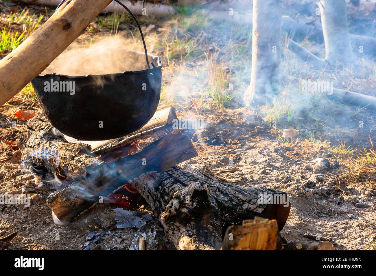 cottura a vapore vecchio vaso all'aperto. cucina e campeggio. avventure all'aperto concetto. cauldron battuto sul fuoco campo Foto Stock