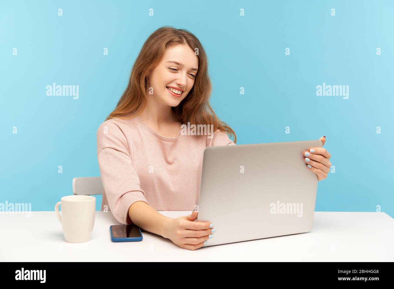Bella donna con un sorriso affascinante guardando lo schermo del laptop, piacevole parlare in videochiamata, intervista online lavoro, conferenza da casa ufficio. io Foto Stock
