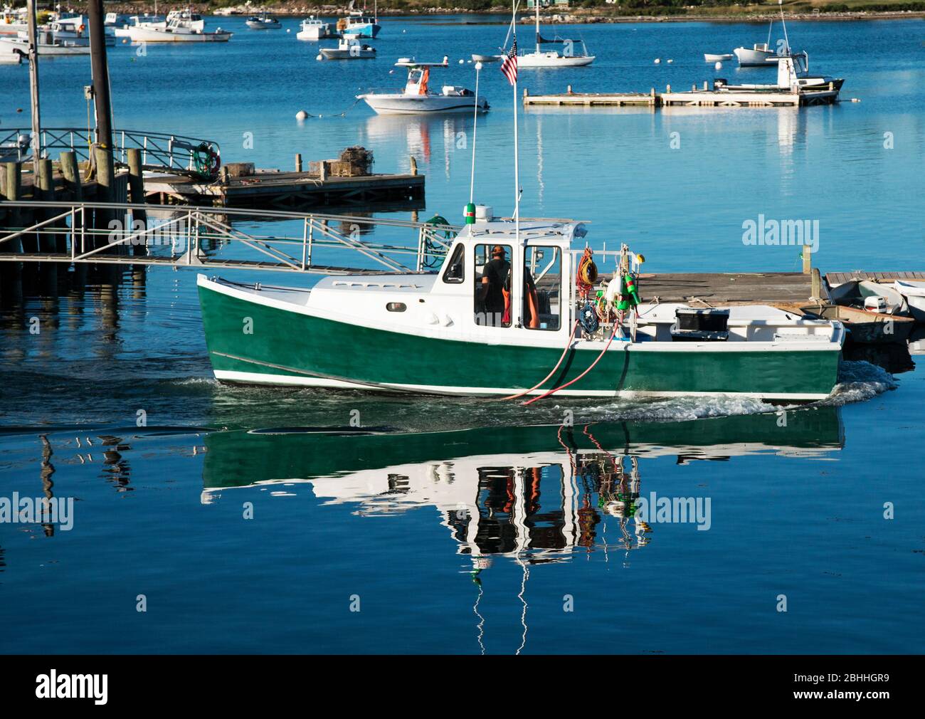 Un pescatore sta sostenendo la sua barca dai moli al crepuscolo, dopo una lunga giornata di recupero aragoste dalla baia. Foto Stock