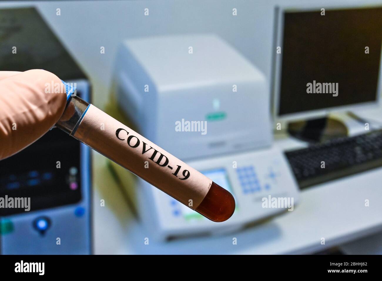 Test PCR in tempo reale su COVID-19. Una provetta con un campione sullo sfondo del dispositivo di amplificazione. Foto Stock