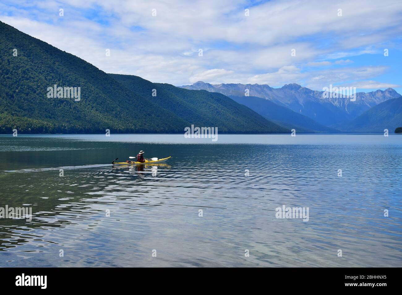 Un uomo in canoa gialla che si addita sul lago Rotoroa. Montagne sullo sfondo. Nelson Lakes National Park, Tasman, Nuova Zelanda, South Island. Foto Stock