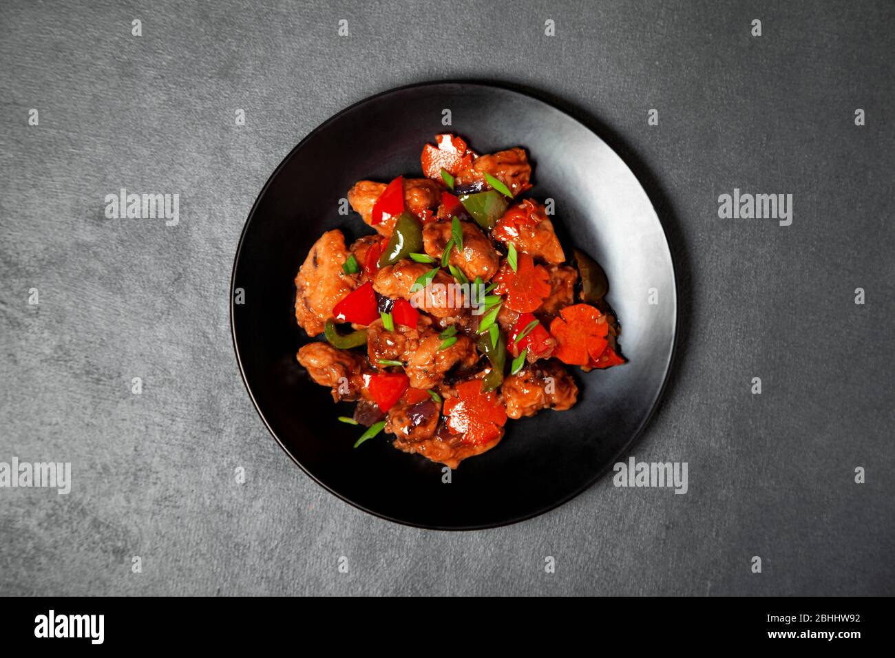 Pollo Manchuriano con verdure su un piatto nero. Vista dall'alto Foto Stock