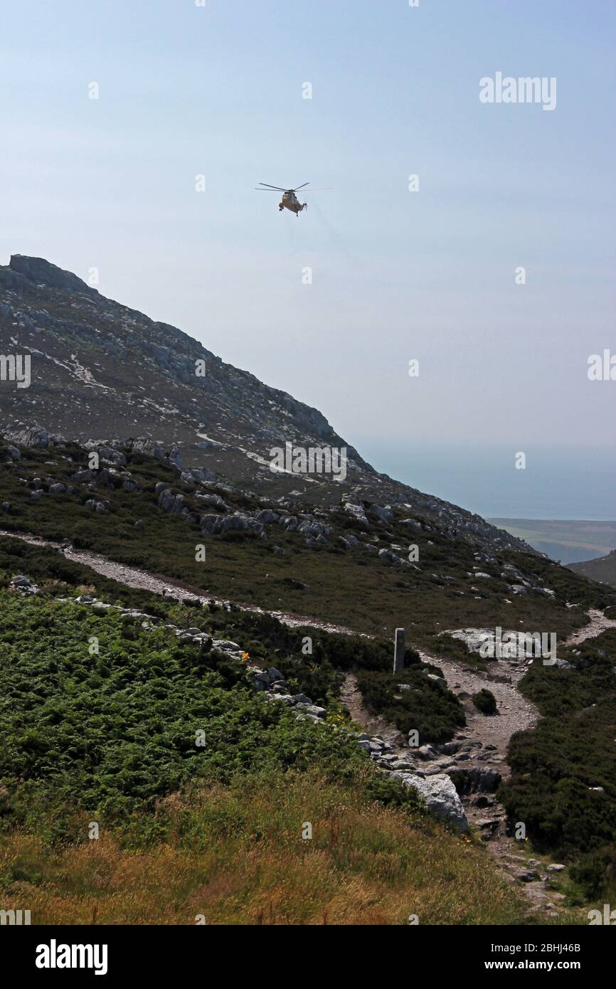 RAF elicottero di salvataggio che pratica manovre sopra Holyhead montagna, Anglesey, Galles Foto Stock