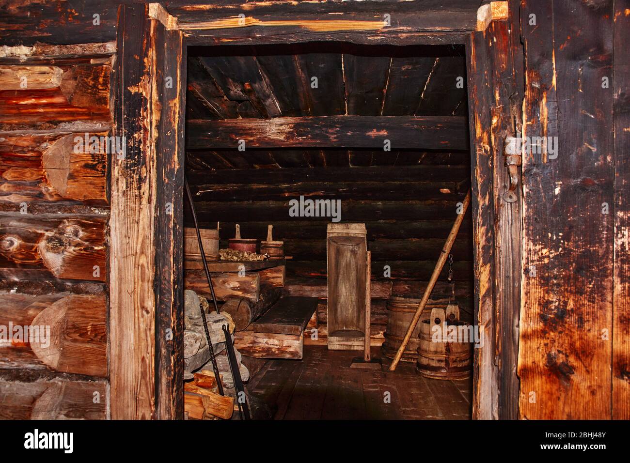 Attraverso la porta si può vedere la struttura interna di un fienile rurale in legno.Inside sono oggetti domestici e utensili utilizzati dalla famiglia nella vita quotidiana Foto Stock
