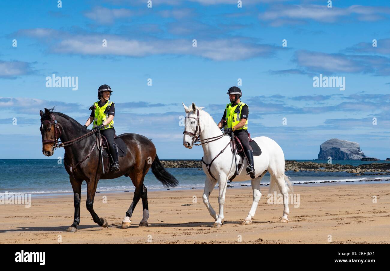 North Berwick, Scozia, Regno Unito. 26 aprile 2020. Polizia montata pattugliando le spiagge di North Berwick in East Lothian questo pomeriggio. Horses Inverness (scuro) ed Edinburgh viaggiarono dalle loro scuderie a Stewarton in Ayrshire per la passeggiata di oggi. Le spiagge erano molto tranquille e il compito principale dei cavalli era posare per le fotografie con le poche persone all'aperto. Nella foto: Polizia montata sulla spiaggia con Bass Rock in lontananza. Iain Masterton/Alamy Live News Foto Stock