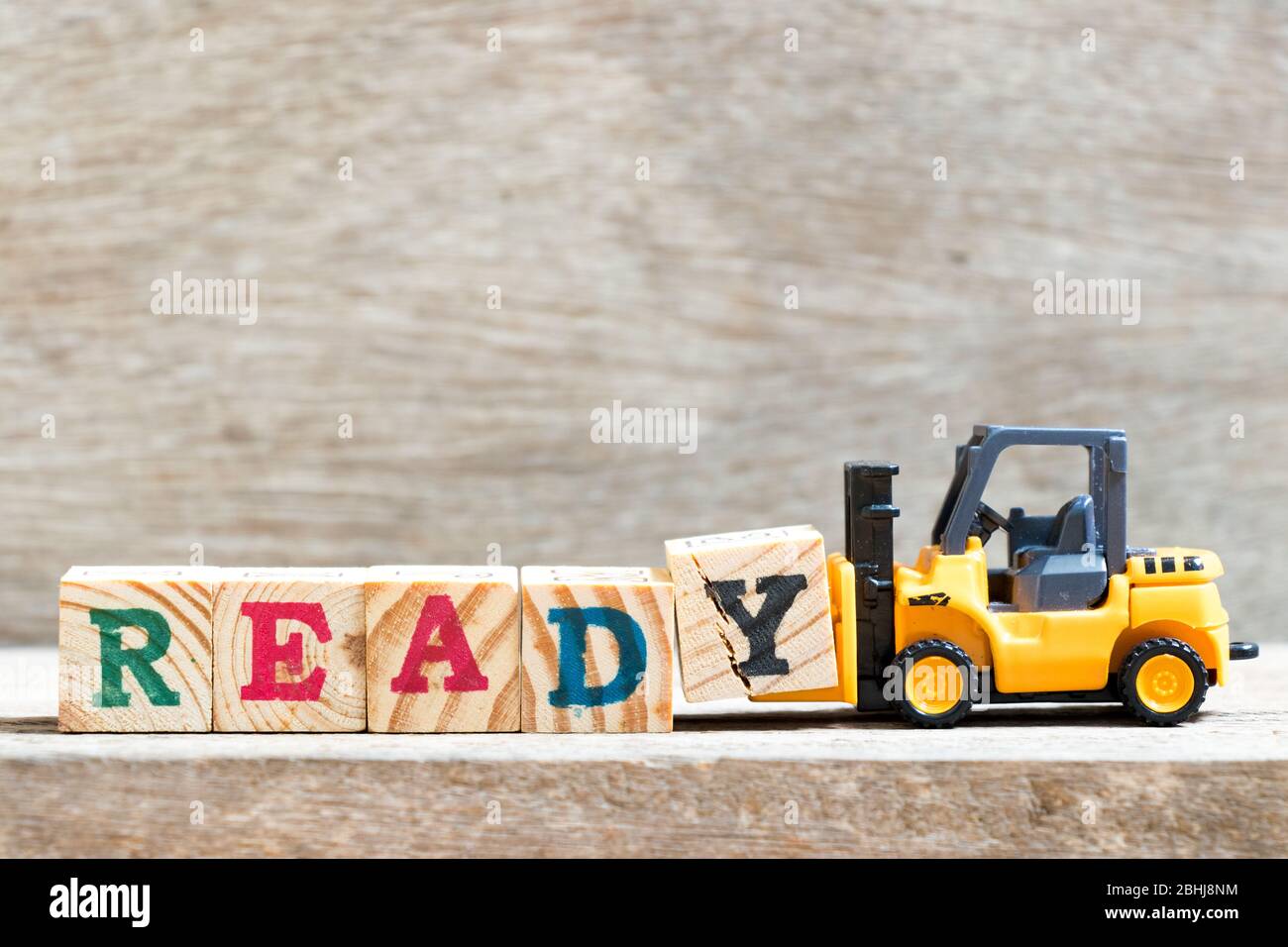 Giocattolo carrello elevatore tenere lettera blocco y per completare parola pronto su sfondo legno Foto Stock