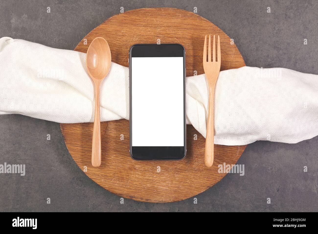 Smartphone con forchetta e cucchiaio su asse di legno. Concetto di cibo Foto Stock