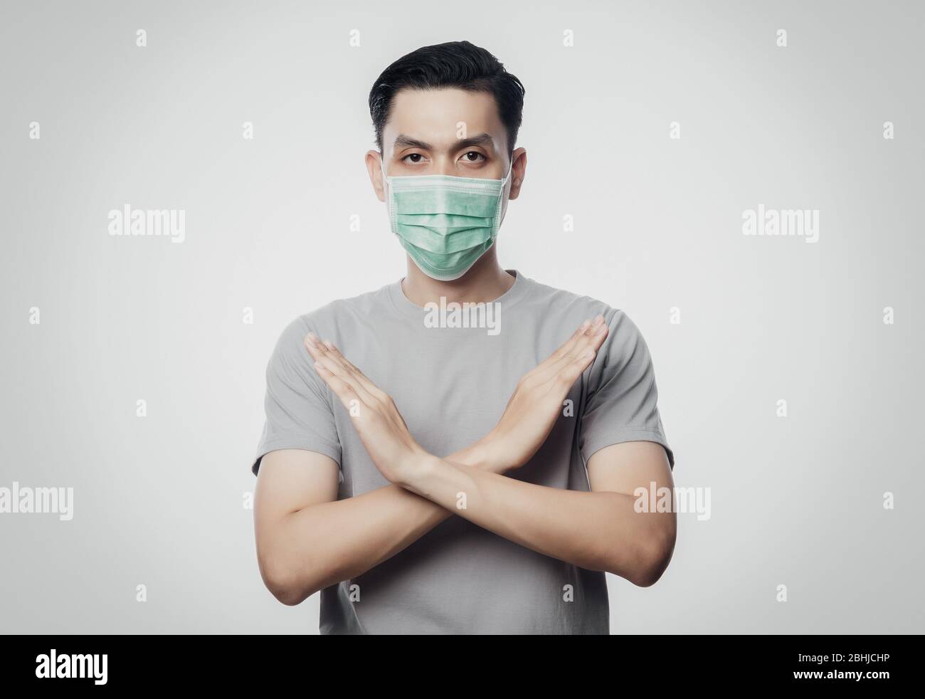 Giovane asiatico uomo che indossa la maschera igienica gesturing stop per prevenire le infezioni, 2019-nCoV o coronavirus. Malattie respiratorie trasmesse dall'aria come la lotta di pm 2.5 Foto Stock