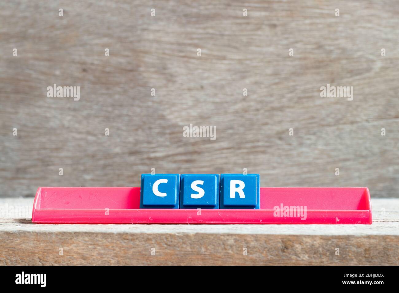 Lettera di mattonella su scaffale rosso in parola CSR (abbreviazione di responsabilità sociale d'impresa) su sfondo legno Foto Stock