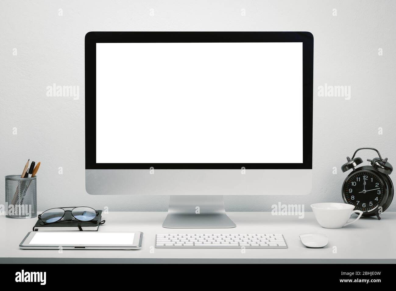 Elegante area di lavoro con schermo vuoto per computer e tablet per il mobile up sulla scrivania con tastiera, mouse, orologio, occhiali e cancelleria. Foto Stock