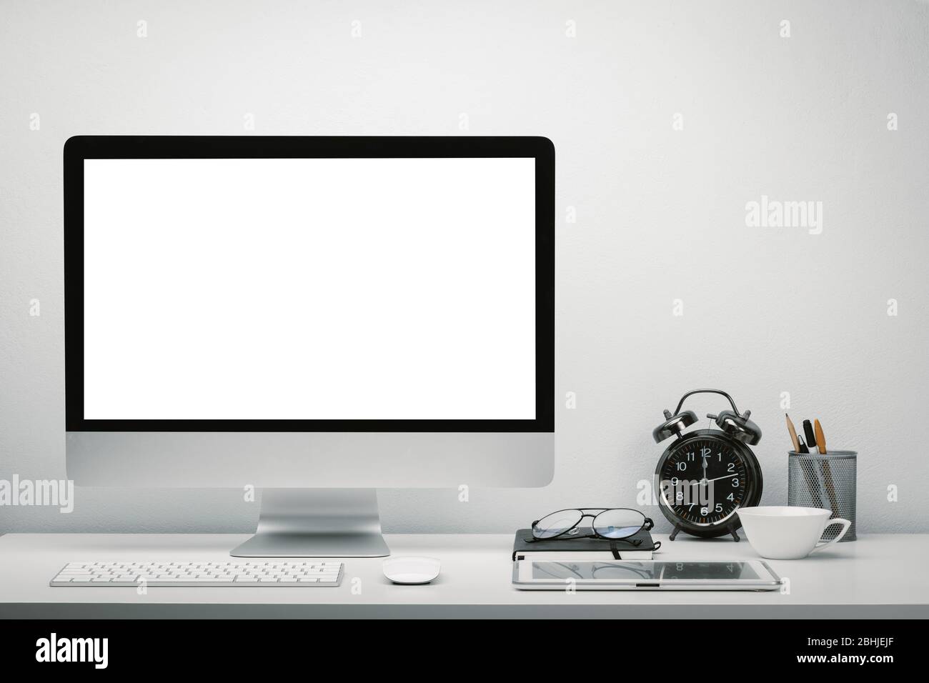 Elegante area di lavoro con schermo vuoto per computer e tablet per il mobile up sulla scrivania con tastiera, mouse, orologio, occhiali e cancelleria. Foto Stock