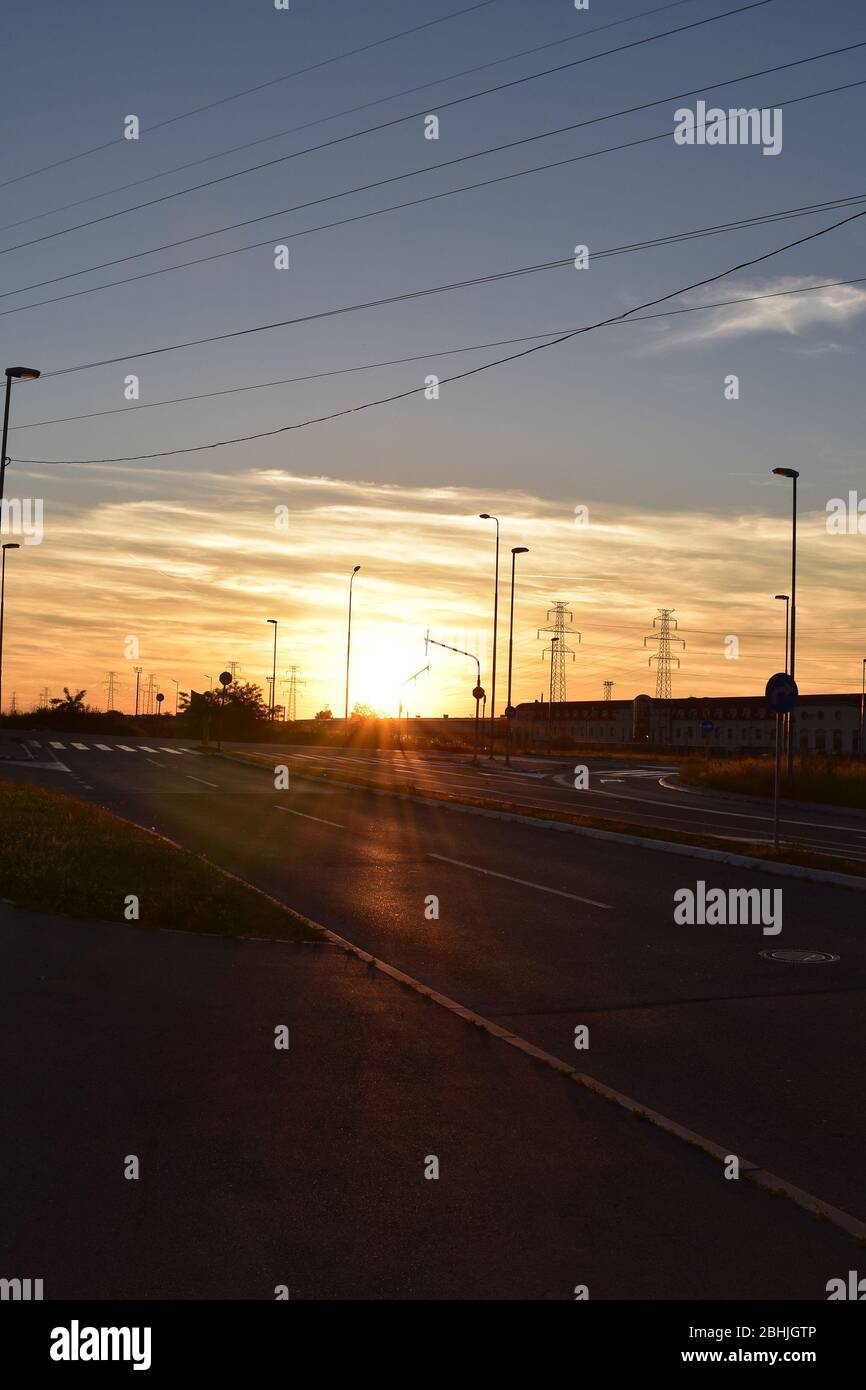 Tramonto e colore arancione del cielo e sottile strato di nuvole, sopra l'intersezione città vuota Foto Stock