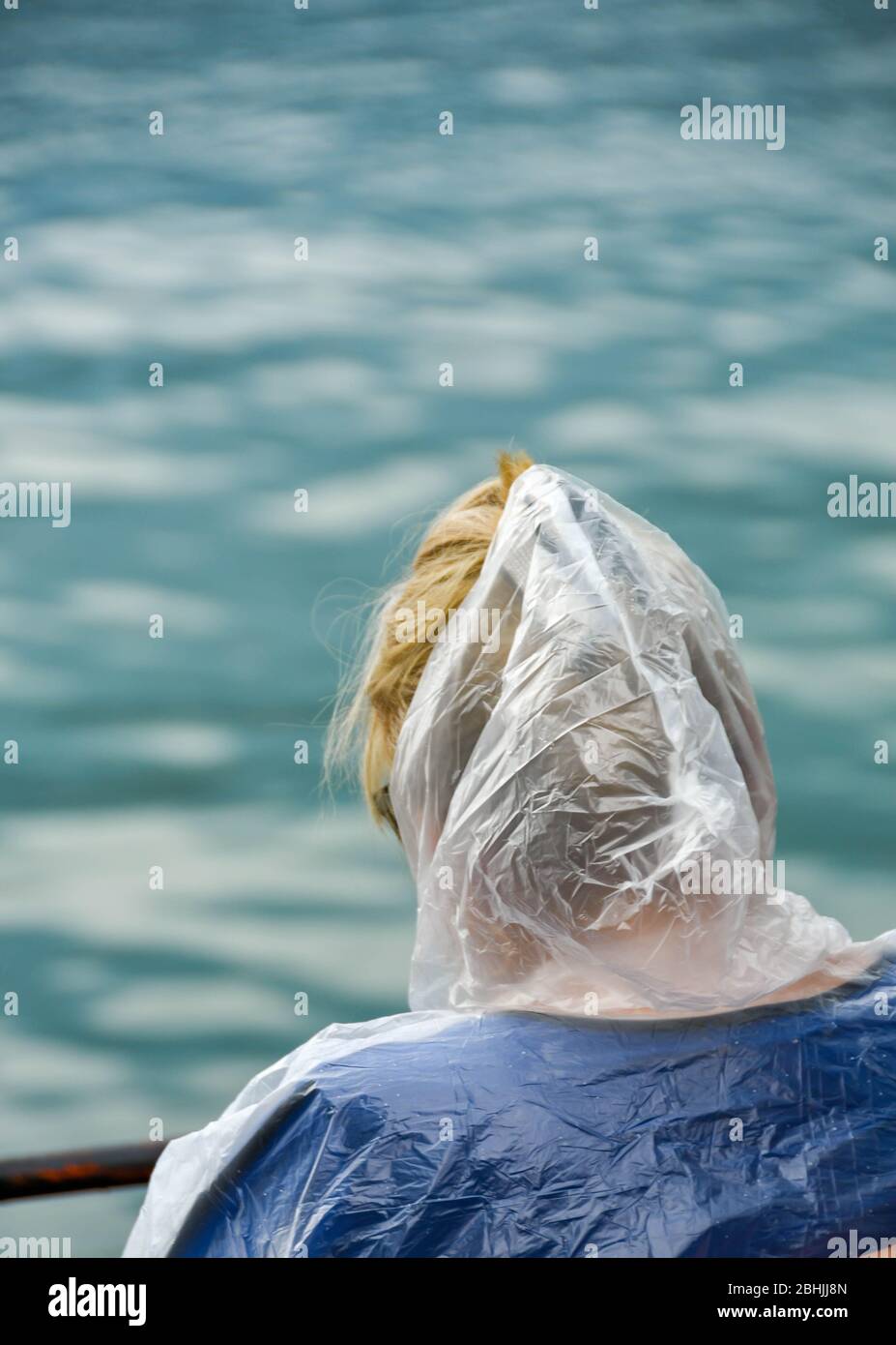 LAGO DI COMO, ITALIA - GIUGNO 2019: Persona con doccia trasparente in plastica sul capo per proteggerlo dalla pioggia. Foto Stock