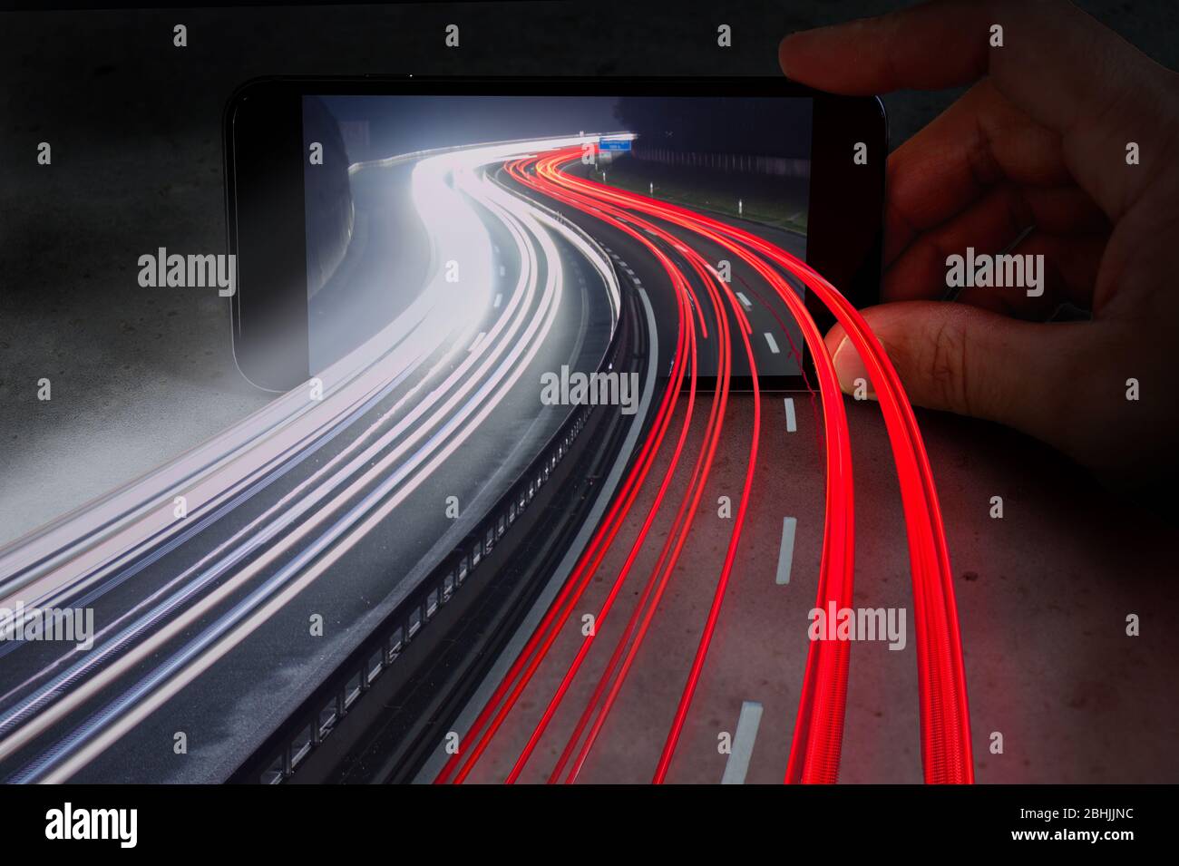 Traffico autostrada sentieri luci provenienti da telefono cellulare che mostra la fusione della realtà virtuale e il mondo reale. Foto Stock