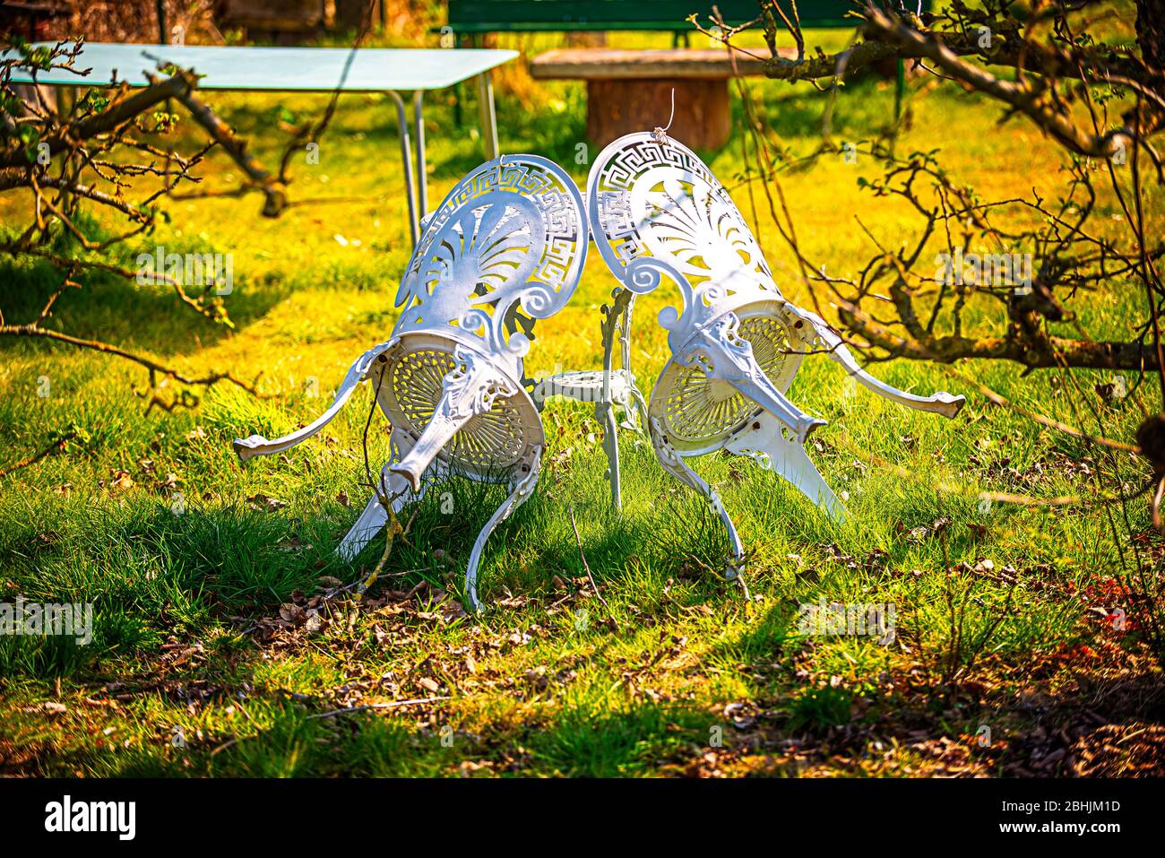 Le sedie da giardino si appoggiano al tavolo in primavera quando il sole splende Foto Stock