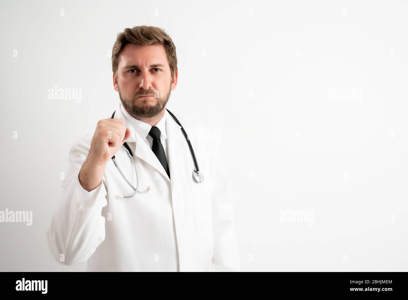 Ritratto di medico maschile con stetoscopio in uniforme medica che mostra il pugno di posa su un fondo bianco isolato Foto Stock