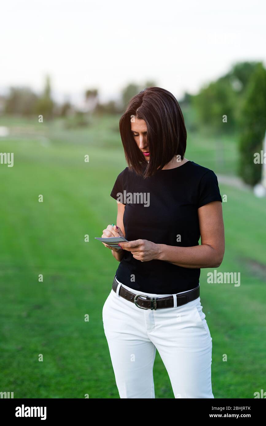 donna golfer che scrive sulla scheda di segno sul campo da golf Foto Stock
