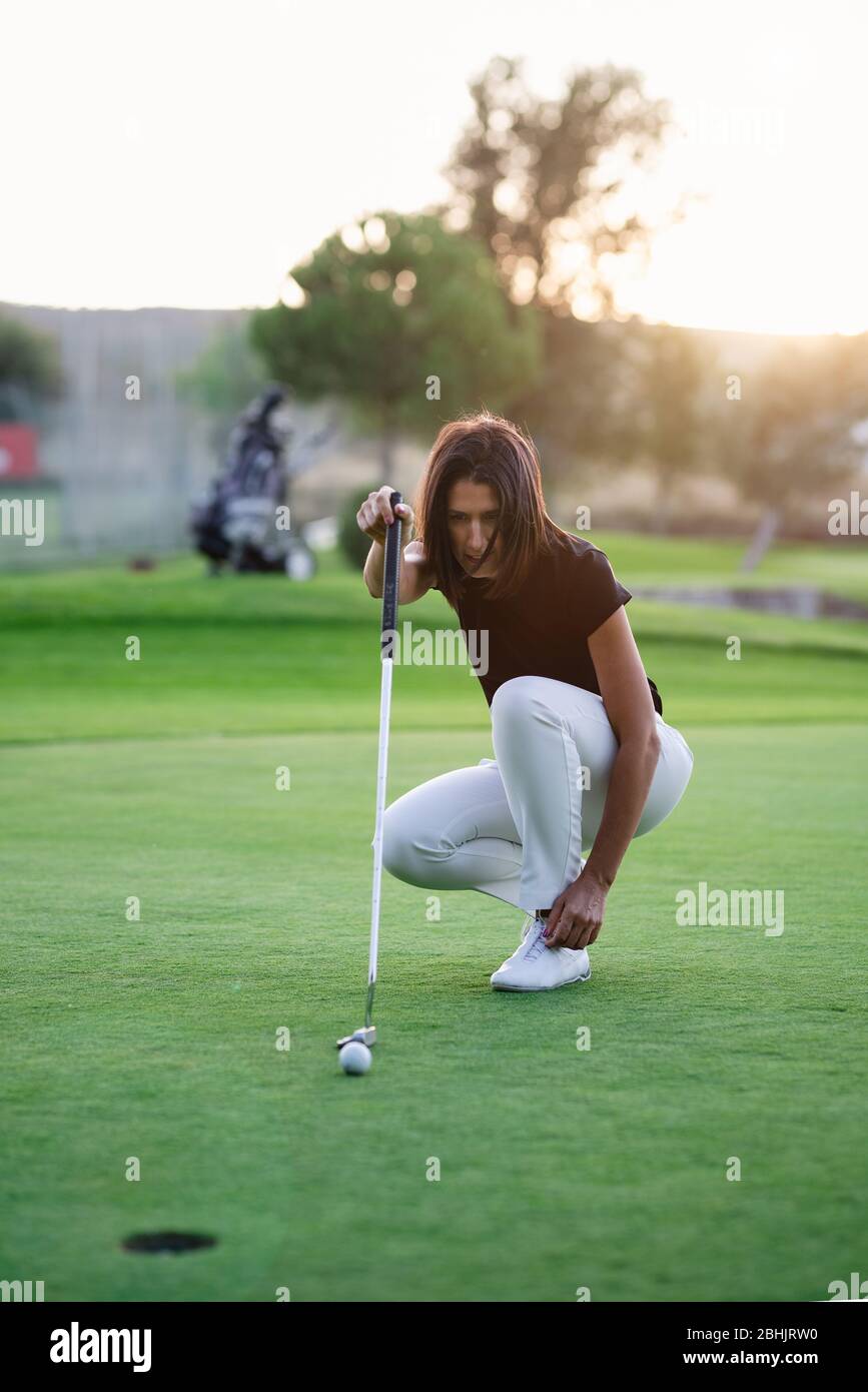 Donna golfer controllare la linea per mettere la sfera di golf sul verde Foto Stock
