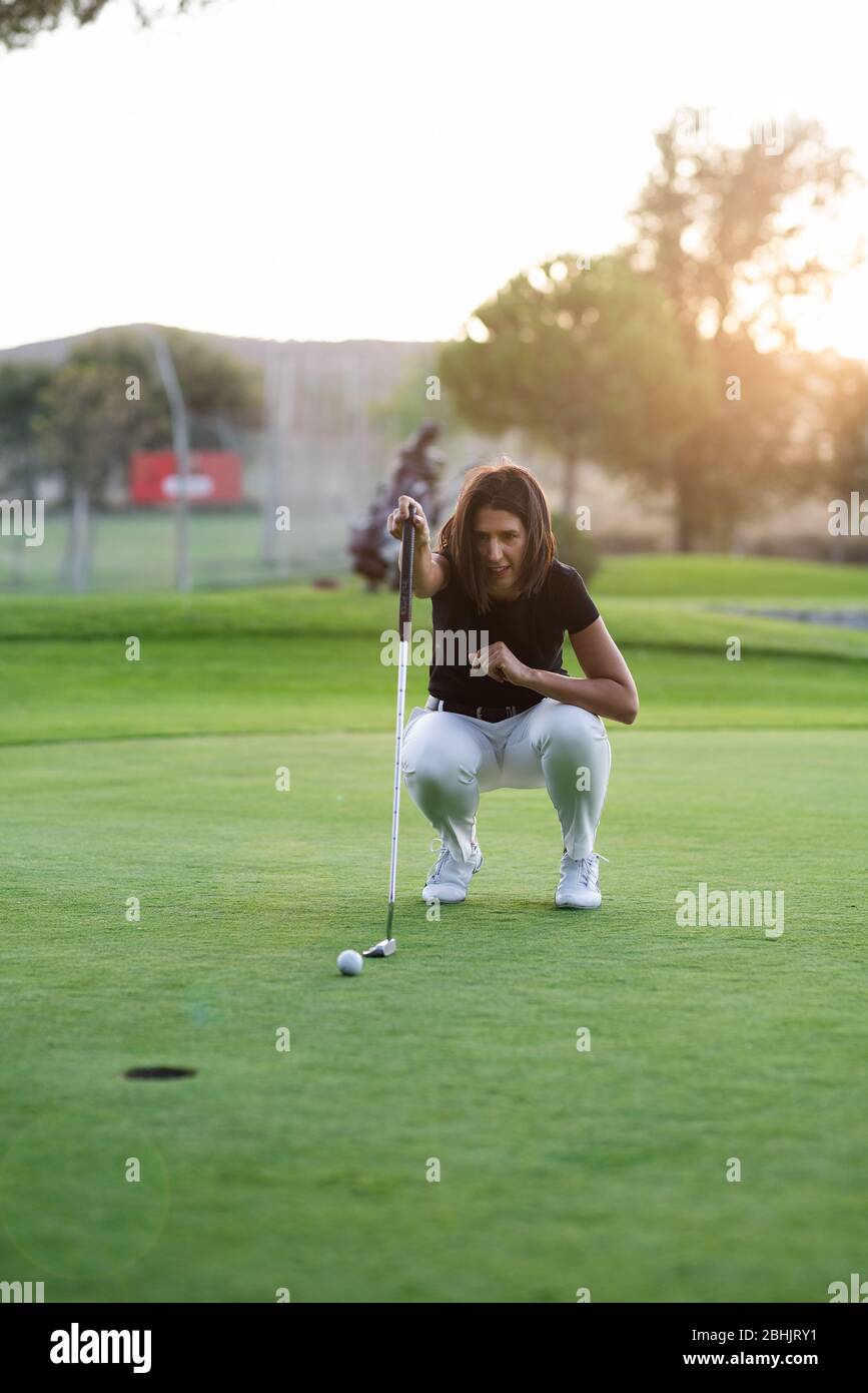 Donna golfer controllare la linea per mettere la sfera di golf sul verde Foto Stock