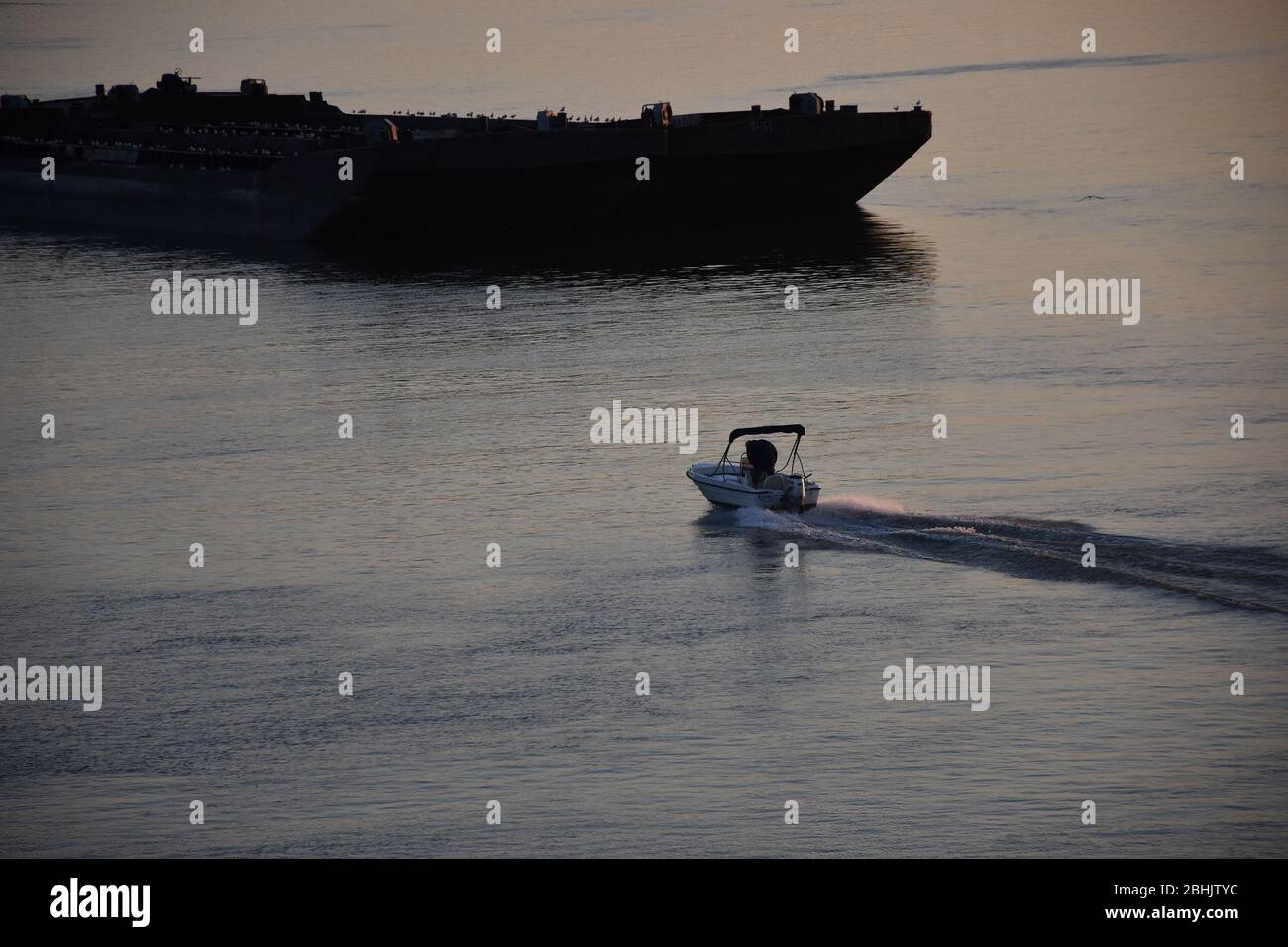 Una grande chiatta sul fiume e una piccola barca privata per incontrare le chiatte Foto Stock