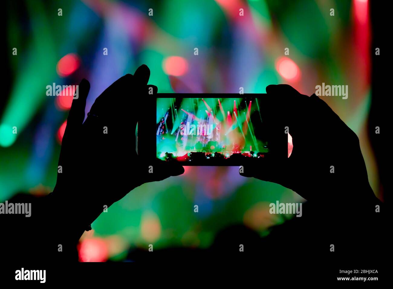 La raccolta della memoria digitale sta perdendo la capacità di essere presente, silhouette di una persona mano che spara il concerto colorato effetti luce palco con s. Foto Stock