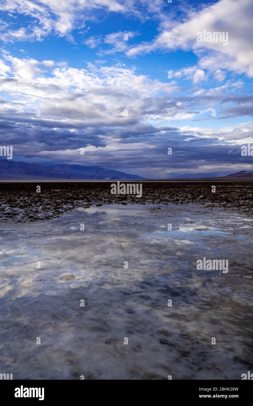 Il cielo e i riflessi del tramonto nelle piscine che rimangono dopo una rara giornata di pioggia al Badwater Basin nel Parco Nazionale della Death Valley. Foto Stock