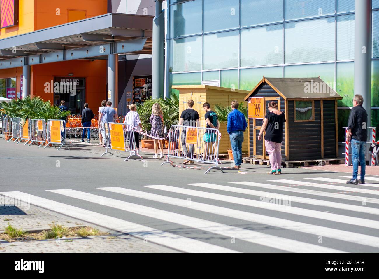 Distanza sociale di persone in attesa in coda di fronte al negozio del mercato delle costruzioni durante il coronavirus covid-19. Nastro adesivo sul pavimento Foto Stock