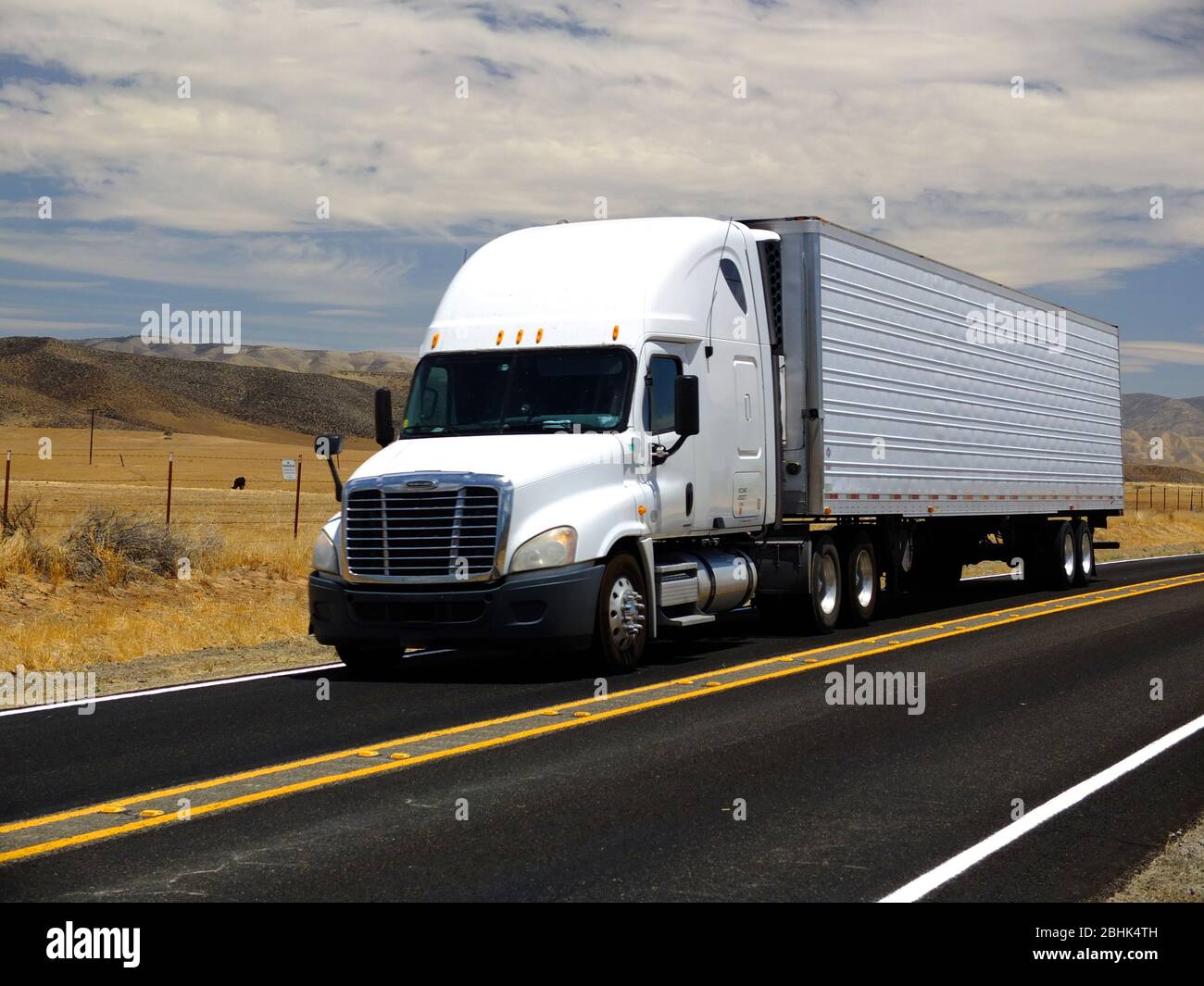 Un singolo camion e rimorchio bianco grande che guida lungo la strada di campagna in cima alla blacktop - autostrada 166 nella California centrale Foto Stock