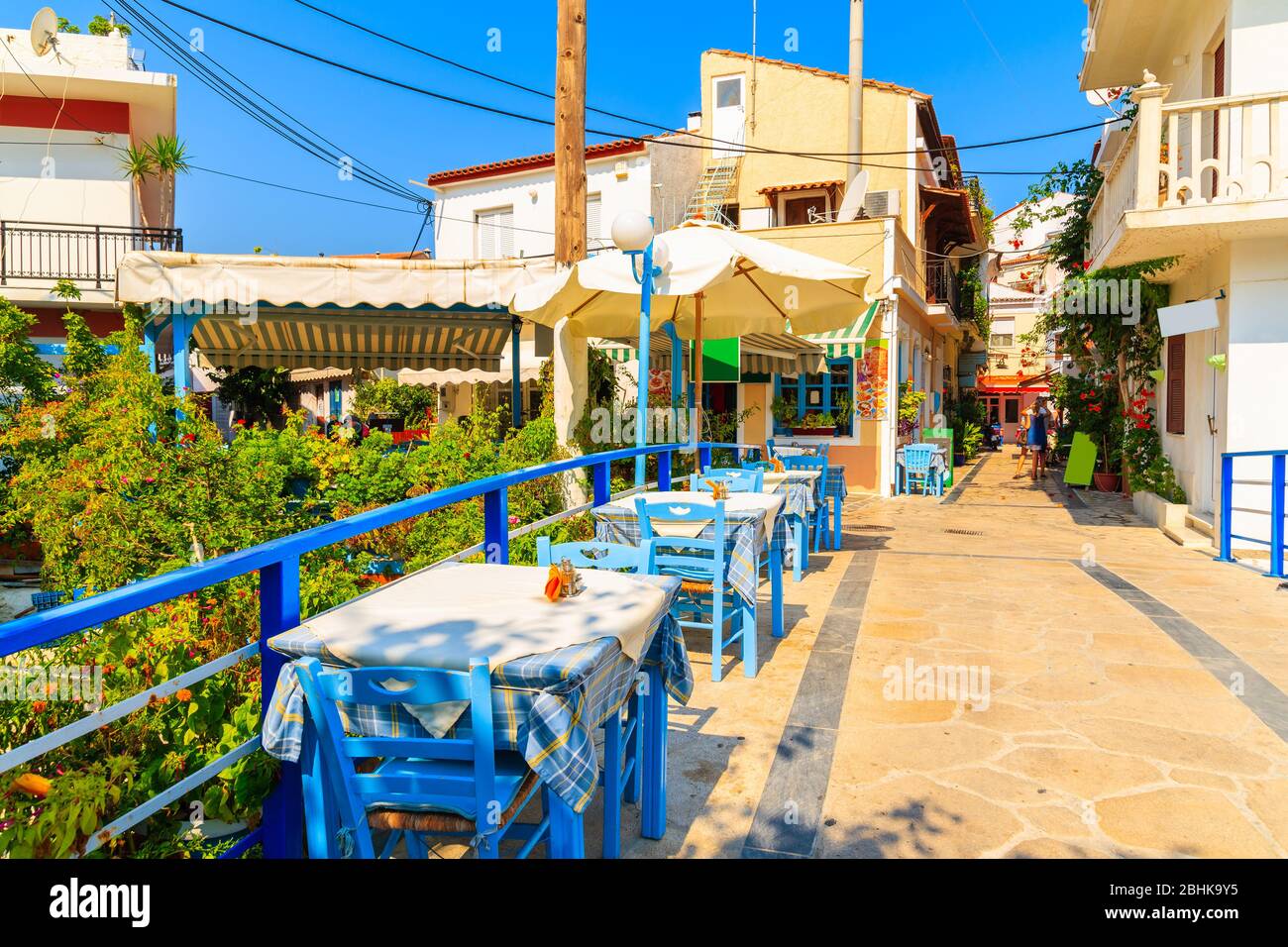 Tavoli con sedie in taverna tradizionale greca sulla strada della città di Kokkari, Grecia Foto Stock