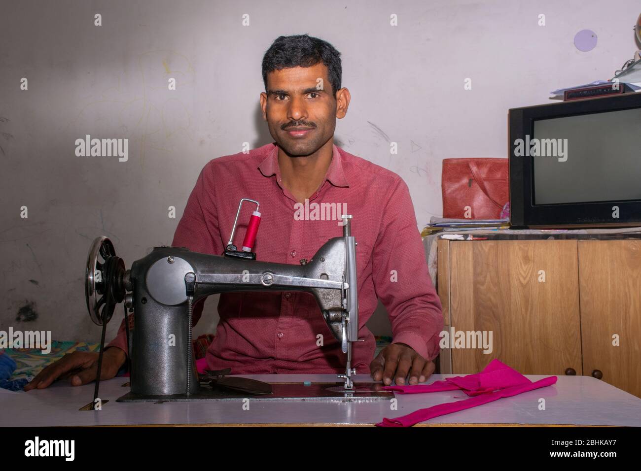 uomo che lavora su una macchina da cucire come sarto Foto Stock