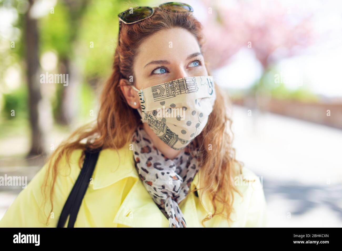 Donna in cappotto giallo e maschera in parco a ritratto durante pandemia Foto Stock