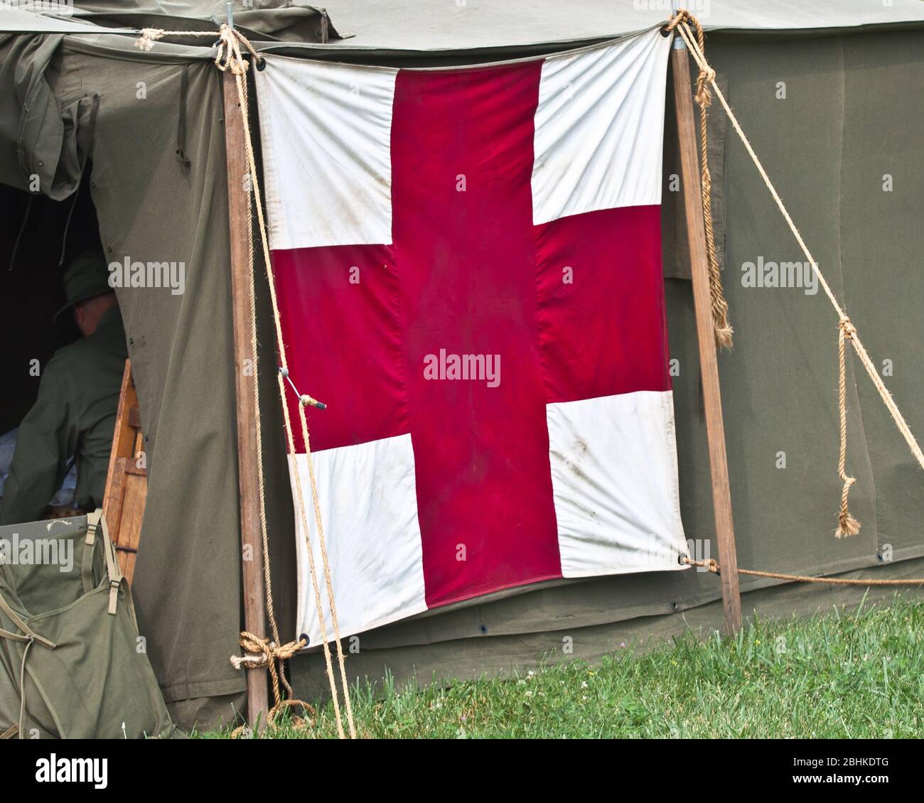 Tenda militare rossa in campo per cure mediche con una grande croce su una tenda verde. Foto Stock