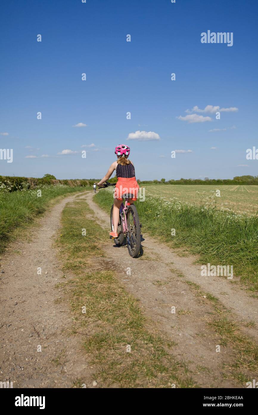 Le ragazze giovani fuori per un giro in bicicletta sulle cremagliere della fattoria, Oxfordshire, Inghilterra Foto Stock