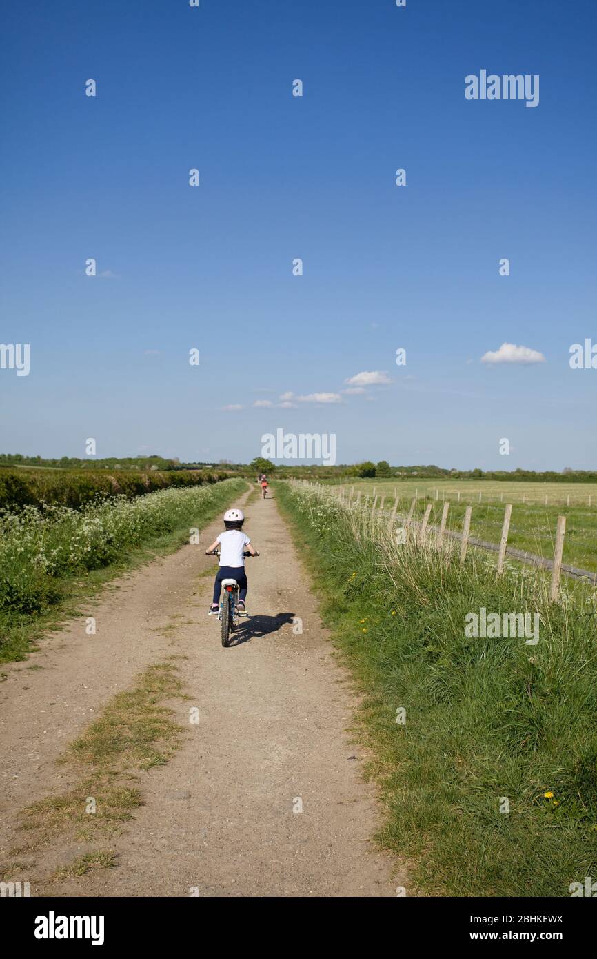 Giovane ragazza in bicicletta su una pista sterrata, Inghilterra Foto Stock