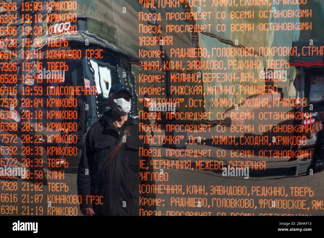 Un uomo in maschera legge il bordo di informazioni con il programma dei treni commuter alla stazione ferroviaria di Leningradsky a Mosca durante l'epidemia del Coronavirus del romanzo COVID-19 in Russia Foto Stock