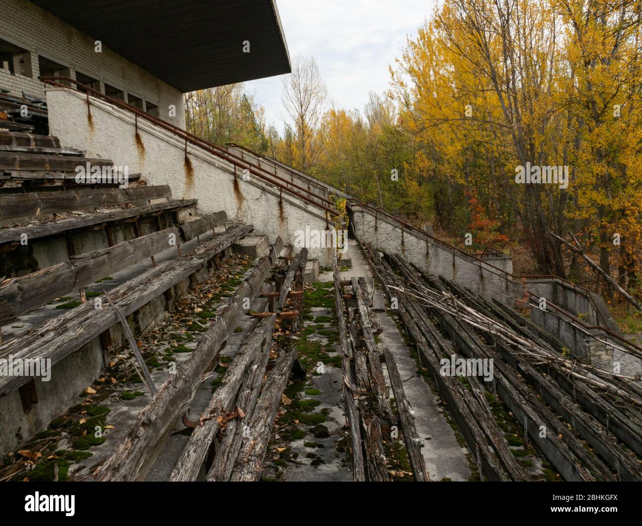 Abbandonata tribuna decadente dello stadio Avangard, presa dalla natura nella città fantasma Pripyat nella zona di esclusione di Chernobyl. Ucraina Foto Stock