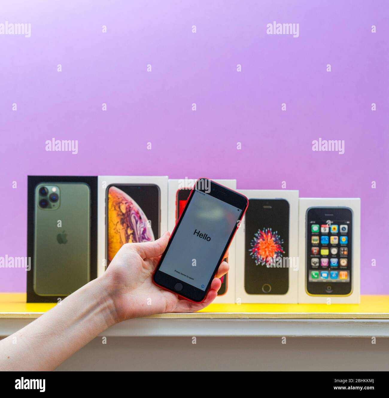 Parigi, Francia - 26 aprile 2020: Donna mano che tiene ultimo iPhone se 2020 telefono rosso con più pacchetti schede di Apple computer iPhone smartphpone iPhone 3gs, se 2016, XS e 11 Pro Foto Stock