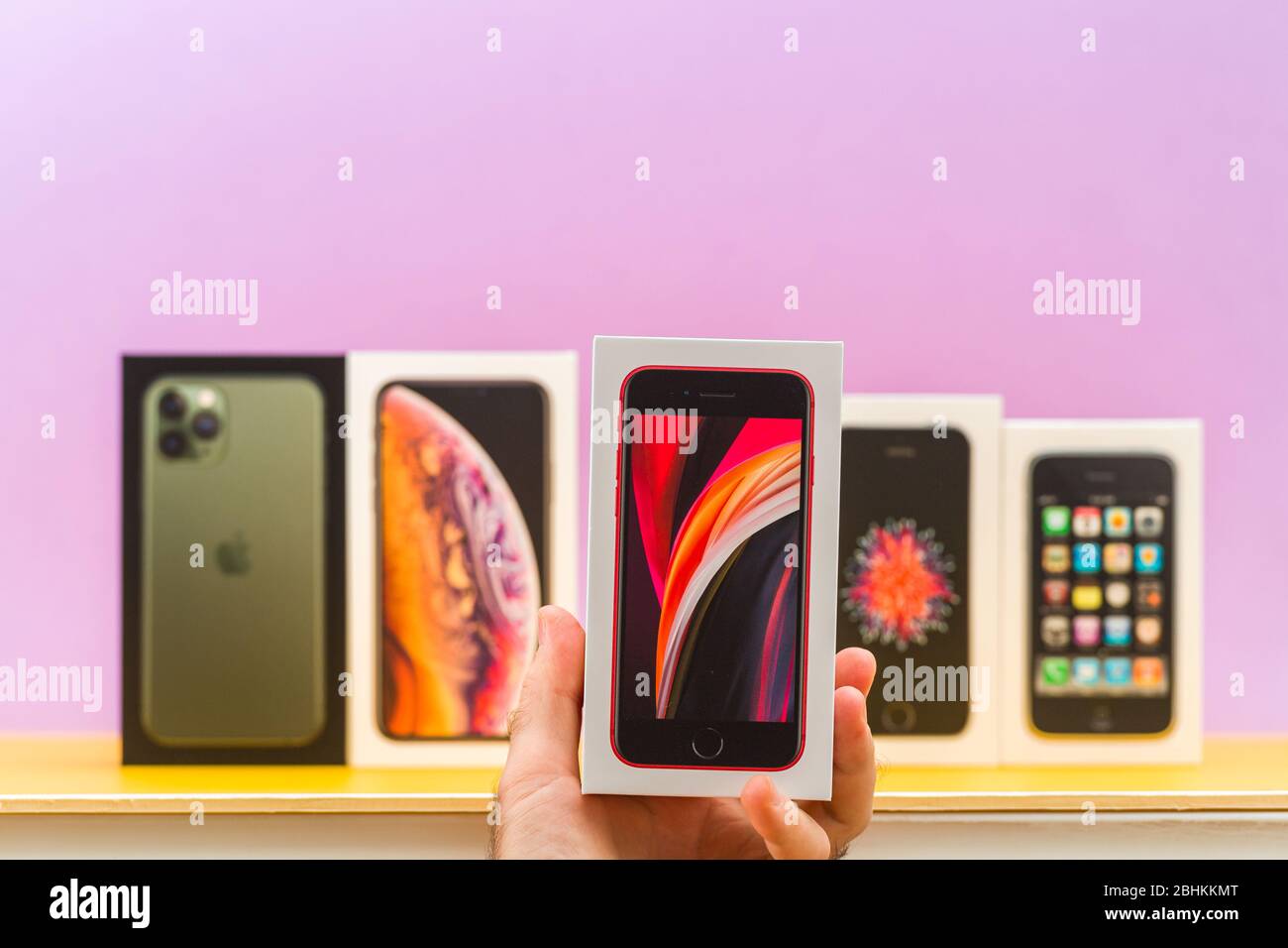 Parigi, Francia - 26 aprile 2020: Uomo che detiene se 2020 scatola telefono con più pacchetti cartoncino di Apple computer iphone smartphpone iPhone 3gs, se 2016, se 2020, XS e 11 Pro con triple fotocamere - collezione vintage e nuova Foto Stock